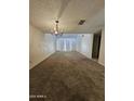Spacious living room featuring neutral carpet, modern lighting, and access to the patio at 189 Laguna E Dr, Litchfield Park, AZ 85340