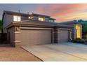 View of the home's three car garage with spacious driveway and desert landscaping at 20432 N 87Th Dr, Peoria, AZ 85382