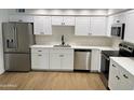 Modern kitchen with stainless steel appliances, white cabinetry, quartz countertop, and wood flooring at 3517 E Blanche Dr, Phoenix, AZ 85032
