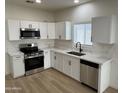 Well-lit kitchen featuring stainless steel appliances, white cabinets, and elegant marble countertops at 5635 S 11Th Dr, Phoenix, AZ 85041