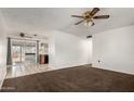 Open-concept living area leads into kitchen with carpet, tile flooring and ceiling fan at 635 W Flower Ave, Mesa, AZ 85210