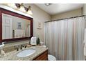 Cozy bathroom featuring granite counters, decorative mirror, and a shower with curtain at 6448 E Des Moines St, Mesa, AZ 85205