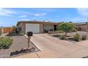 Single-story home with a well-maintained yard, long driveway, and attached two car garage at 6448 E Des Moines St, Mesa, AZ 85205