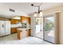 Bright eat-in kitchen with wood cabinets, breakfast bar, and sliding door to patio at 10137 W Forrester Dr, Sun City, AZ 85351