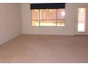 A bright living room showcasing neutral carpet, large windows, and a glass paneled door at 1412 E Oakland St, Gilbert, AZ 85295