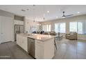 Open concept kitchen and living area with stainless steel appliances, a breakfast bar, and plenty of natural light at 16935 W Sheridan St, Goodyear, AZ 85395
