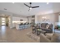 Spacious living room and kitchen area with modern lighting, a ceiling fan, and an eat-in kitchen island at 16935 W Sheridan St, Goodyear, AZ 85395