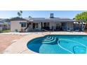 Backyard pool featuring a tanning ledge and solar panels on the house for energy efficiency at 3833 W Phelps Rd, Phoenix, AZ 85053