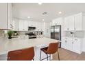Bright kitchen with stainless steel appliances, white cabinets, an island with a quartz countertop, and modern bar stools at 4117 W Camino Acequia Ave, Phoenix, AZ 85051