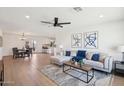 Inviting living room with wood-look floors, neutral decor, a ceiling fan, and an open layout connected to dining area at 4117 W Camino Acequia Ave, Phoenix, AZ 85051