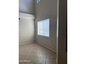 Bright living room with a large window and high ceilings with neutral paint and tile flooring at 7422 W Superior Ave, Phoenix, AZ 85043