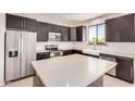 Modern kitchen with stainless steel appliances, dark cabinetry, a large island, and white herringbone backsplash at 802 W Buist Ave, Phoenix, AZ 85041