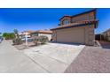 Home exterior with a spacious driveway, gravel landscaping, and a well-maintained yard under a clear blue sky at 11215 W Heatherbrae Dr, Phoenix, AZ 85037