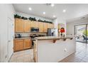 Well-lit kitchen featuring wood cabinets, stainless appliances, granite countertops, a breakfast bar, and tile flooring at 4414 W Monte Way, Laveen, AZ 85339