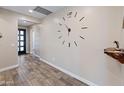 Hallway with wood-look tile flooring, a large clock, and access to various rooms at 549 E Balao Dr, Phoenix, AZ 85085