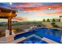 Backyard with pool, water feature, fire pit, and mountain views at dusk at 826 E Buist Ave, Phoenix, AZ 85042