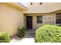 Inviting front entry featuring decorative shrubs and a secure, dark-stained front door at 10468 W Palmeras Dr, Sun City, AZ 85373