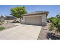 Single-story home boasts a neutral facade, tile roof, two-car garage, and low-maintenance landscaping at 15960 W Indigo Ln, Surprise, AZ 85374