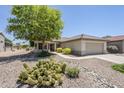 Well-maintained single-story home featuring desert landscaping, tiled roof, and a two-car garage at 15960 W Indigo Ln, Surprise, AZ 85374