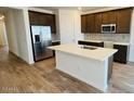 Modern kitchen features stainless steel appliances, granite countertops, an island with sink, and hardwood style floors at 25133 W Wayland Dr, Buckeye, AZ 85326