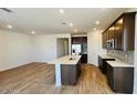 Bright kitchen boasts stainless steel appliances, an island with sink, granite countertops and beautiful hardwood style floors at 25133 W Wayland Dr, Buckeye, AZ 85326