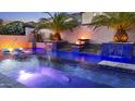 Beautiful pool showcasing fire bowls, waterfalls, palm trees, and comfortable lounge chairs for ultimate relaxation at 2985 N Point Ridge Rd, Buckeye, AZ 85396