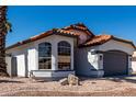 Charming single-story home featuring a terracotta roof, arched windows, and low-maintenance landscaping at 5125 W Wickiup Ln, Glendale, AZ 85308