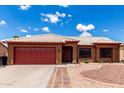 Charming single-story home featuring a red garage door, desert landscaping, and a white tiled roof at 6302 E Portia St, Mesa, AZ 85215