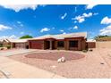 Charming single-story home featuring a red garage door, beautiful desert landscaping, and a white tiled roof at 6302 E Portia St, Mesa, AZ 85215