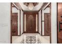 Elegant foyer with a decorative tile floor, a chandelier, and a wooden front door at 11737 N 143Rd Dr, Surprise, AZ 85379