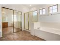 Well-lit bathroom featuring a bathtub, standing shower and a large mirror at 13599 W Monte Vista Rd, Goodyear, AZ 85395