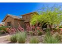 A charming single-Gathering home features desert landscaping, a stone facade, and mature desert trees at 3331 N Acacia Way, Buckeye, AZ 85396