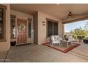 Inviting covered front porch with seating area, ceiling fan, decorative door, and a welcoming ambiance at 3331 N Acacia Way, Buckeye, AZ 85396