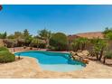 Backyard pool with lush landscaping and rock waterfall feature at 3331 N Acacia Way, Buckeye, AZ 85396