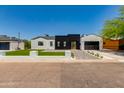 Modern home exterior boasts contrasting black and white accents, lush turf, and a paved driveway at 4246 E Mulberry Dr, Phoenix, AZ 85018