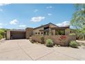Desert home featuring a modern exterior, stone accents, meticulously landscaped yard, and a private driveway at 10651 E Fernwood Ln, Scottsdale, AZ 85262