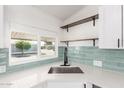 Modern kitchen sink features white countertop, stylish faucet, and open shelving above at 11000 N 91St Ave # 20, Peoria, AZ 85345