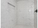 Shower stall featuring white marble tiling, mosaic flooring, and built-in shelving at 11000 N 91St Ave # 20, Peoria, AZ 85345