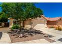 Beige single-story home with a two-car garage, desert landscaping, and a concrete driveway at 11669 W Pine Mountain Ct, Surprise, AZ 85378