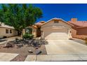 Beige single-story home with a two-car garage, desert landscaping, and a concrete driveway at 11669 W Pine Mountain Ct, Surprise, AZ 85378