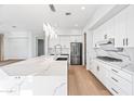 Modern kitchen boasts white cabinetry, quartz countertops, stainless steel appliances, and a spacious island at 1724 W Blue Ridge Way, Chandler, AZ 85248