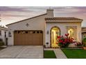 Inviting home exterior featuring a stucco facade, a two-car garage, and a charming arched entryway with vibrant red flowers at 20784 W Minnezona Ave, Buckeye, AZ 85396