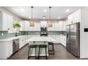 Modern kitchen with white cabinets, stainless steel appliances, large island, and stylish pendant lighting at 2562 N Springfield St, Buckeye, AZ 85396
