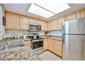 Galley kitchen featuring stainless steel appliances, granite countertops, and light wood cabinets at 5757 W Eugie Ave # 2068, Glendale, AZ 85304
