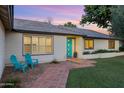 Inviting home featuring a bright teal front door, brick walkway, and cozy blue chairs at 7533 N 8Th St, Phoenix, AZ 85020