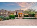 Inviting desert home with stone accents, arched doorway, and professionally landscaped grounds showcasing beauty and elegance at 11548 E Salero Dr, Scottsdale, AZ 85262