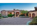 Charming desert home showcasing a stone facade, arched entrance, and mature landscaping for enhanced curb appeal at 11548 E Salero Dr, Scottsdale, AZ 85262