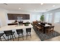 Bright eat-in kitchen with white counters, dark cabinets, an island with bar seating, and a modern dining area at 12633 W Luxton Ln, Avondale, AZ 85323