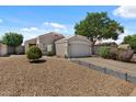 Inviting single-story home with a two-car garage and mature landscaping, including desert-style gravel and healthy greenery at 1703 E Palo Blanco Way, Gilbert, AZ 85296