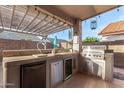 Outdoor kitchen with built-in grill, mini fridge, prep space, and pergola at 18080 W Spencer Dr, Surprise, AZ 85374